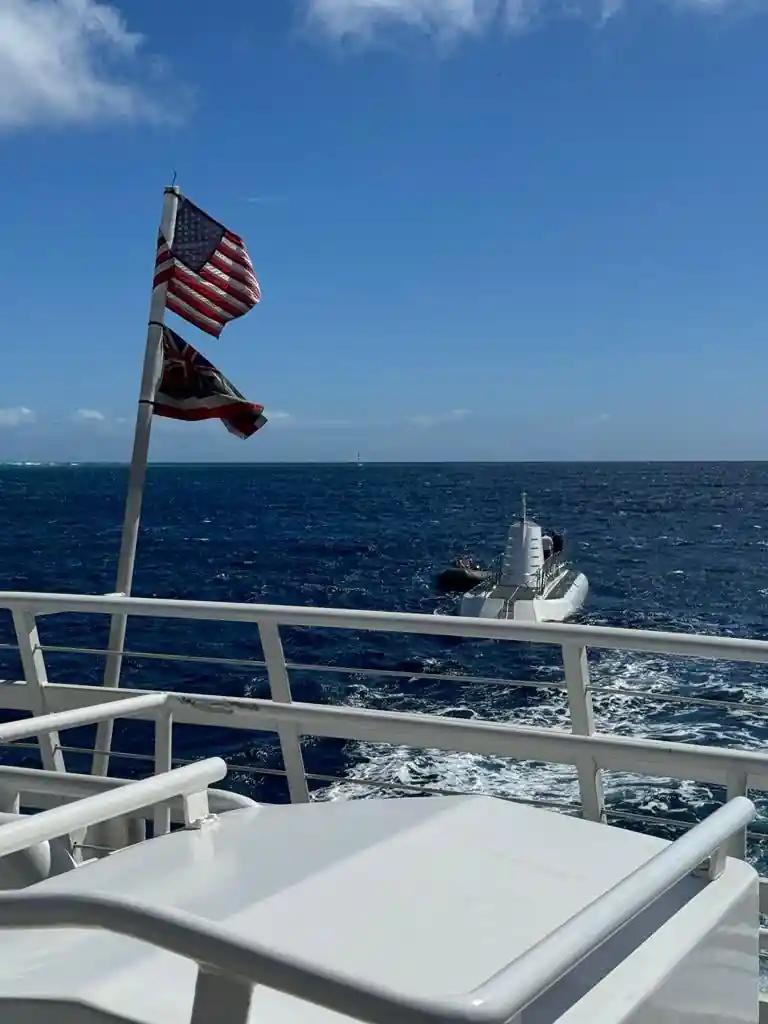 The American flag flying from the transfer boat with the submarine astern