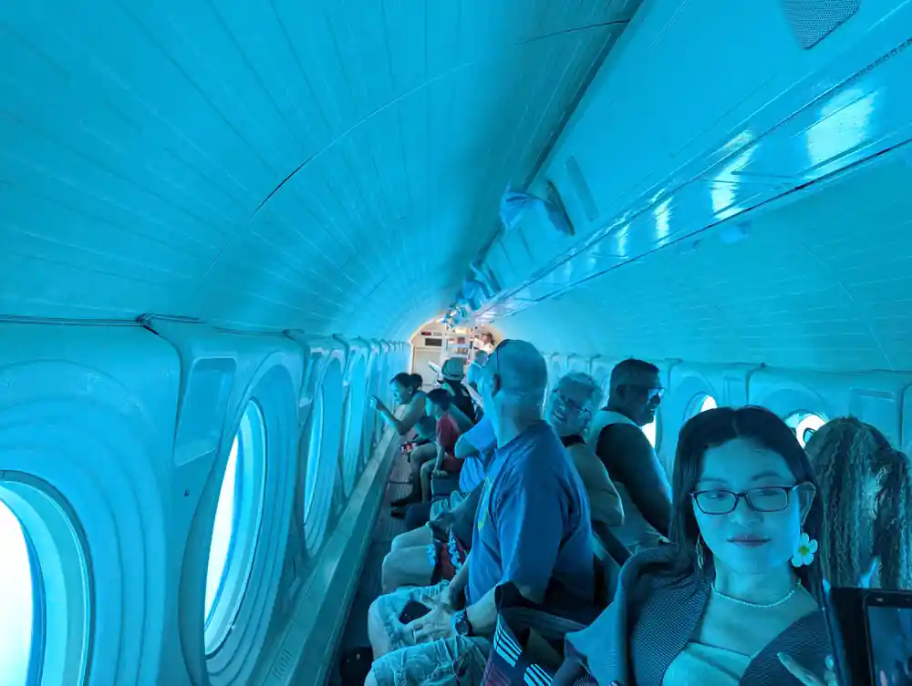 The cabin from the aisle with passengers at the viewports on both sides
