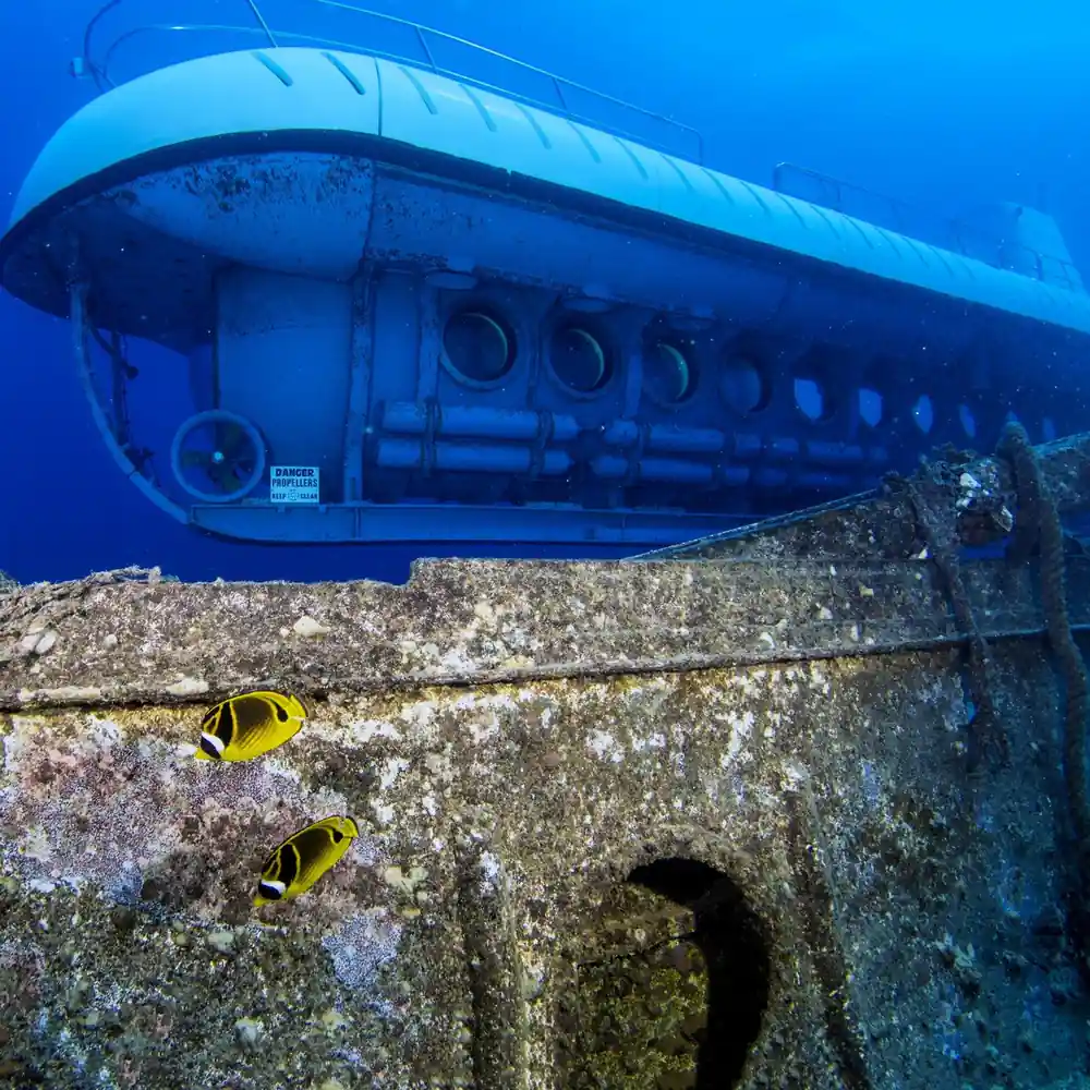 The hull of the submarine beside a concrete structure with two yellow tangs