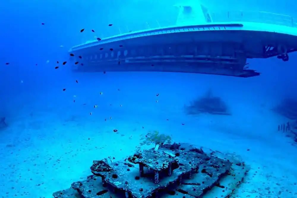 The white hull of the submarine above a wreck on the seabed