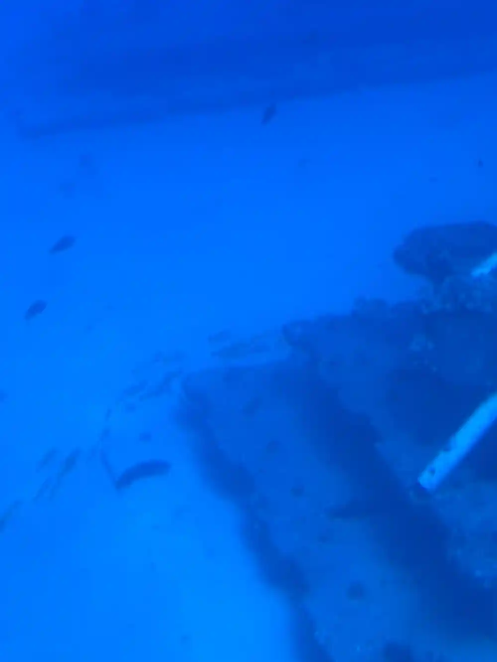 A wreck lying on the sand in open blue water