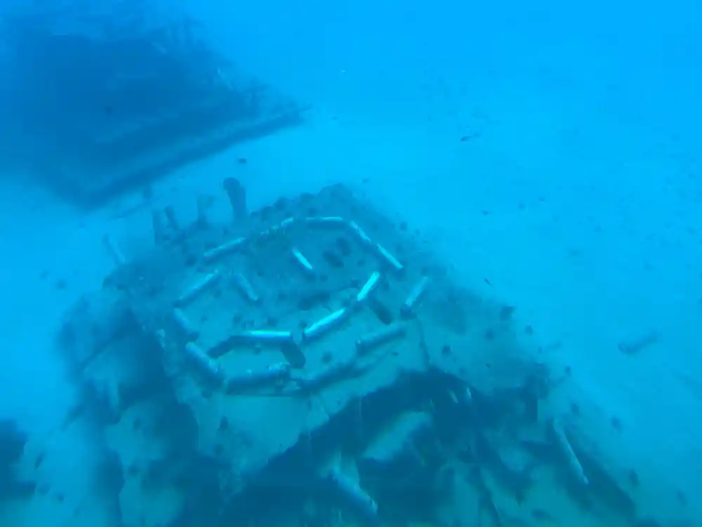 A wreck resting on pale sand in bright water